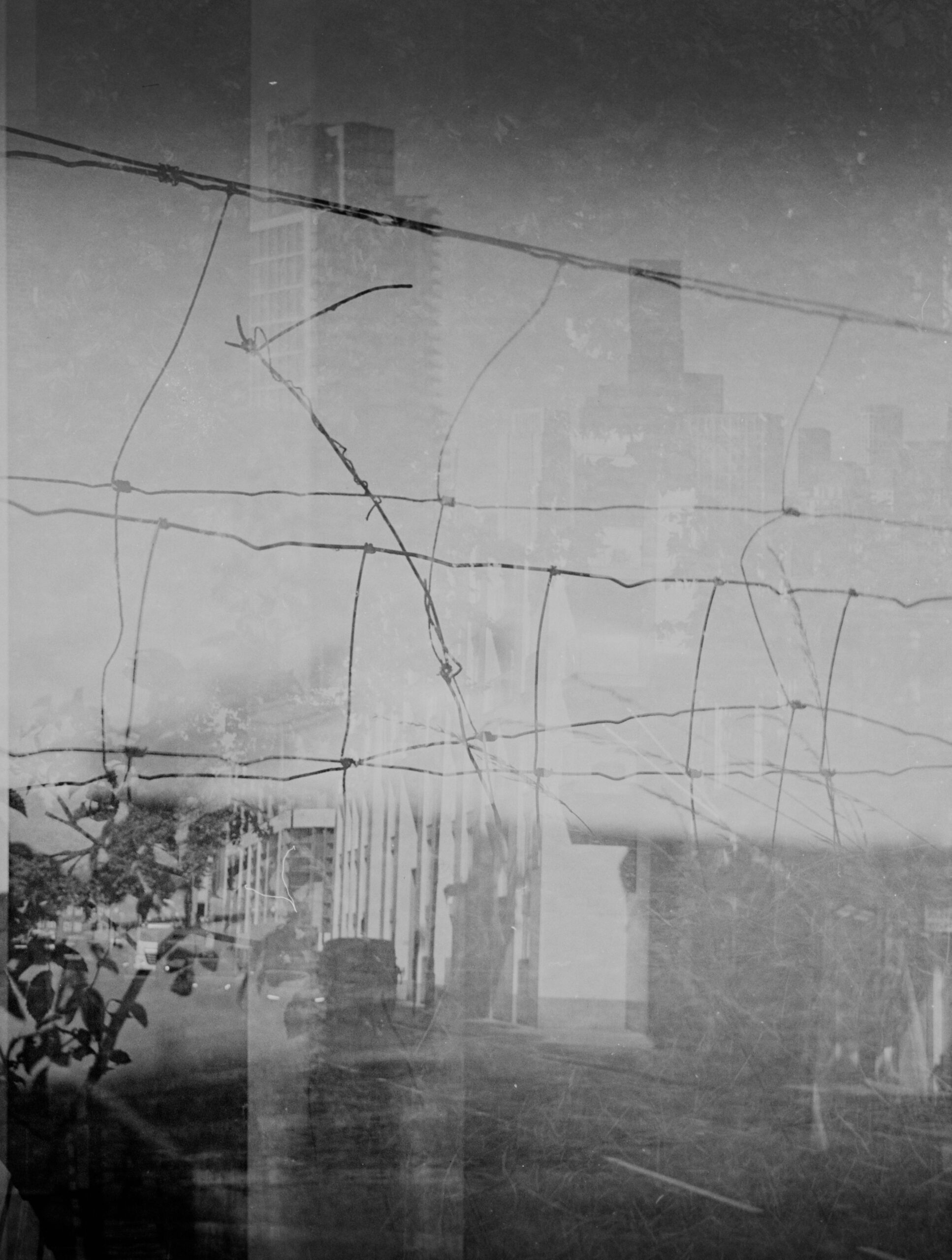 Monochrome urban street scene behind tangled wires