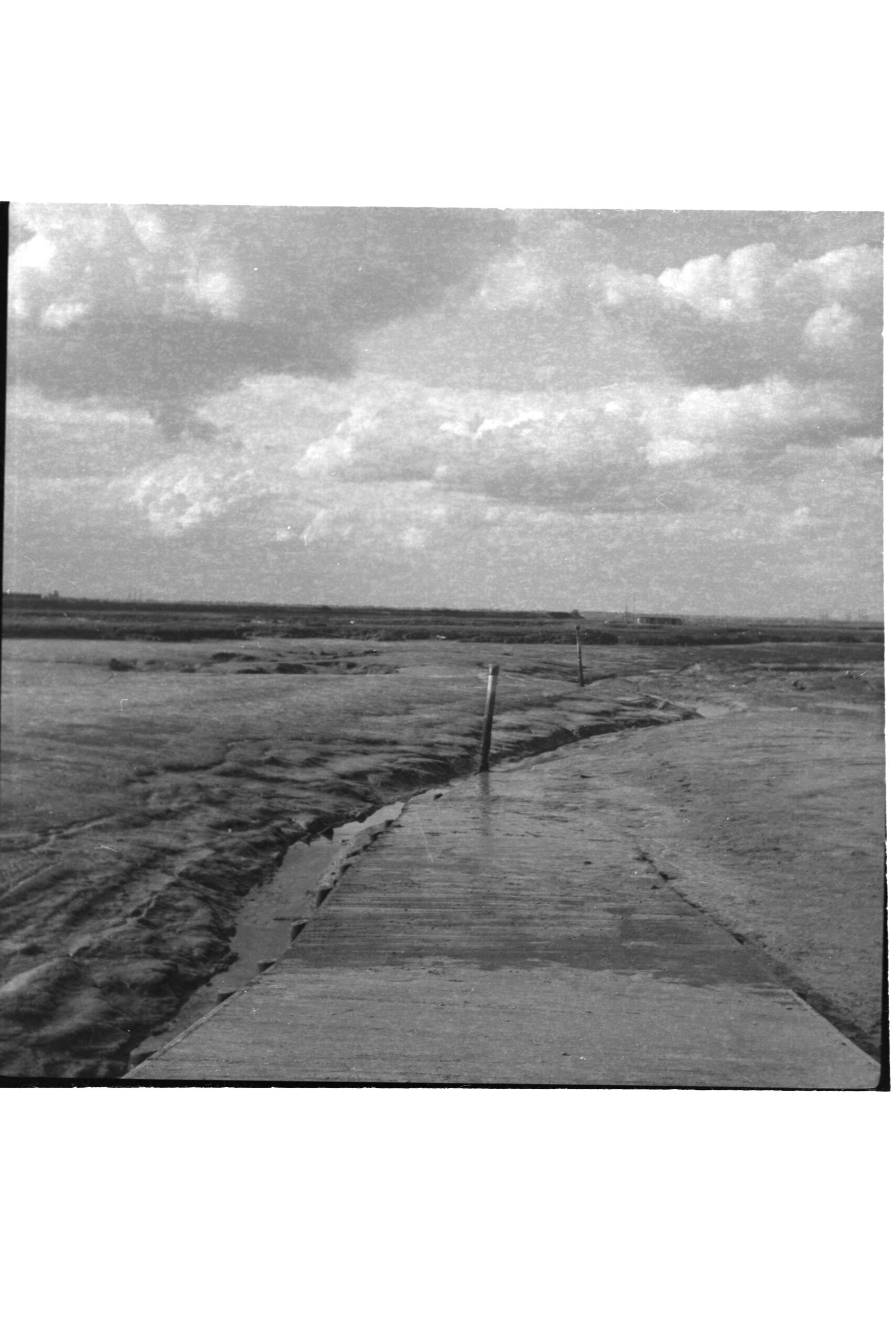 Black-and-white tidal landscape with a walkway leading toward the horizon